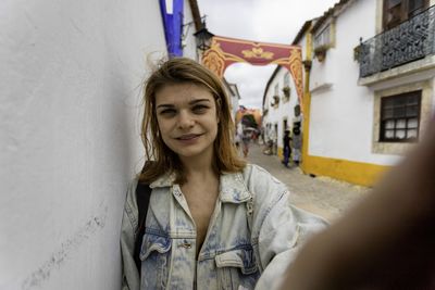 Portrait of smiling woman by wall standing on street