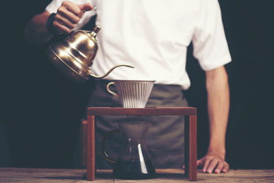 Midsection of man pouring drink in cup