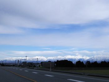 Country road against cloudy sky