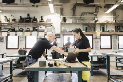 Teacher guiding high school student on project in workshop