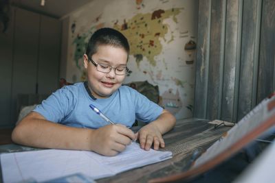 Asian child with glasses study at home, colorful world map, education app, online learning