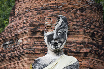 Low angle view of old damaged buddha statue and temple