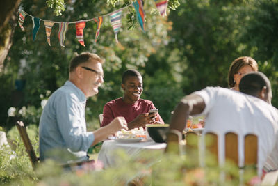 Happy multi-generation family having lunch together in backyard during garden party