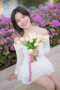 Portrait of young woman standing by plants
