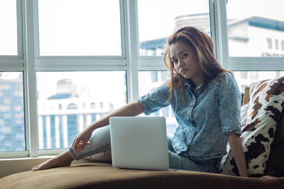 Young woman using phone while sitting on table