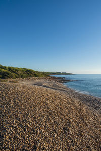 Scenic view of beach against clear blue sky