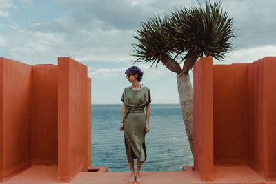 Full length of woman standing at resort against sea