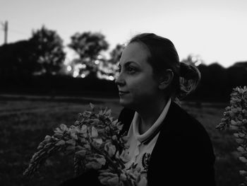 Portrait of young woman looking away against sky