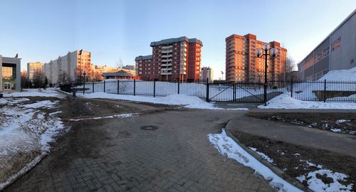 Snow covered buildings in city against clear sky