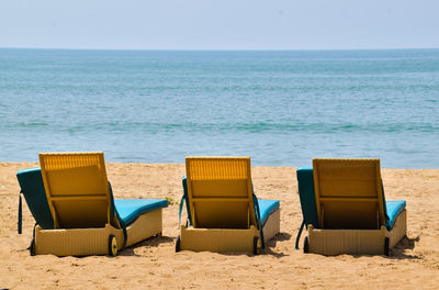 Chairs on beach against clear sky