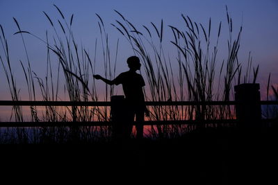 Silhouette man standing by sea against sky during sunset