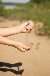 Low section of woman hand on sand