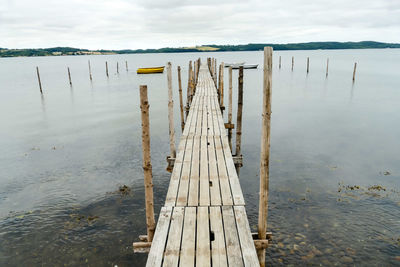 Wooden posts on pier over lake against sky