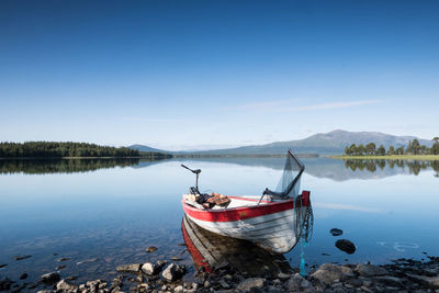 Fishing boat at lake side of clear blue lake in wilderness of scandinavia