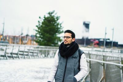 Young man standing by railing during winter