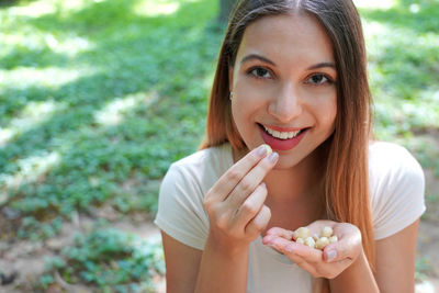 Close-up of healthy girl eating macadamia nuts in the park. looks at camera.