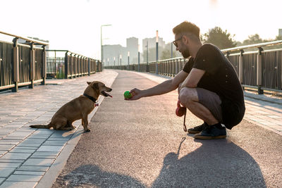 Young man is playing with his dog on empty street in the morning.