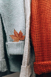 Stack of cozy knitted warm sweater with autumn fall maple leaf. sweaters in retro style. orange 