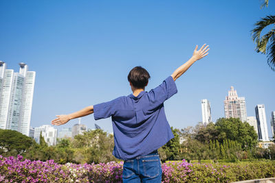 Rear view of person standing on rock against blue sky