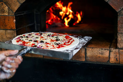 Close-up of person putting pizza in oven at restaurant