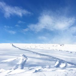 Snow covered landscape against blue sky