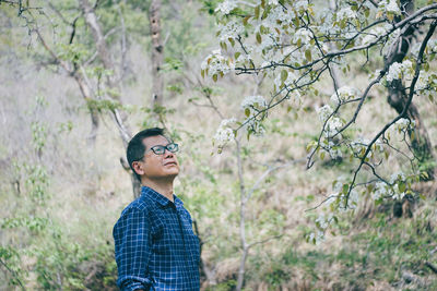 Old man standing against pear tree with flowers 