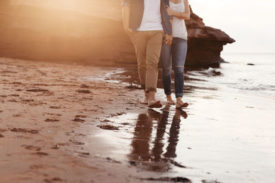 Low section of couple walking on beach