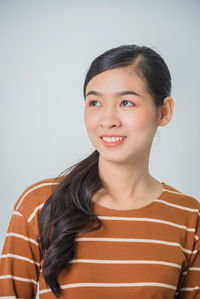 Portrait of a smiling young woman against gray background