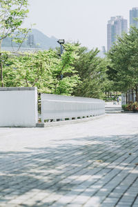 Empty footpath by buildings in city against sky