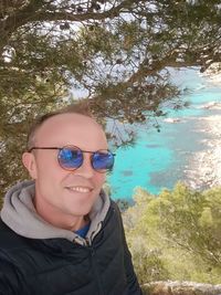 Portrait of smiling man wearing sunglasses against plants