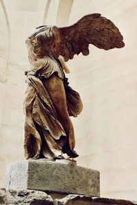 Low angle view of angel statue against wall