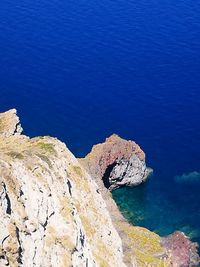 Rock formations by sea against blue sky