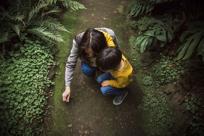 High angle view of mother and son crouching on field at park