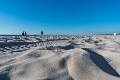 Scenic view of sandy beach against clear blue sky