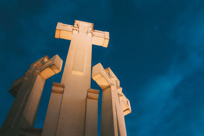 Low angle view of cross on building against blue sky