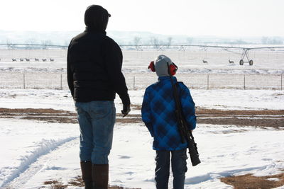 Rear view of people standing on snow covered land