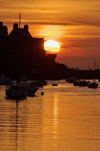 Sailboats moored on sea against sky during sunset