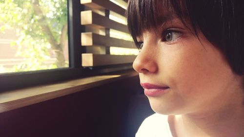 Close-up of boy by window at home