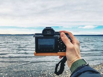 Midsection of man photographing sea against sky