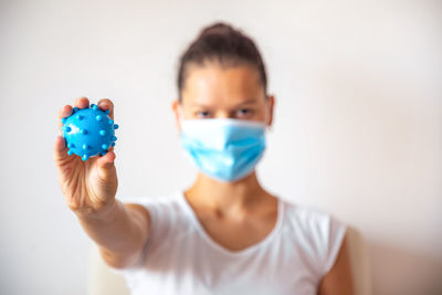 Portrait of young woman holding virus standing at home