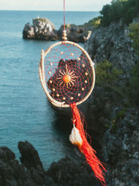 Close-up of rock hanging by sea against sky