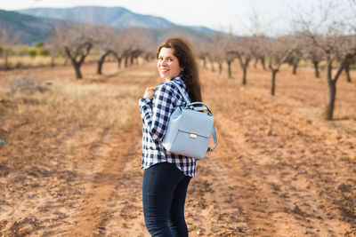 Portrait of smiling young woman standing on land