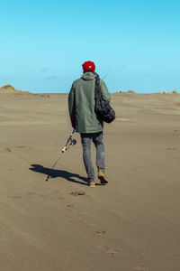 Rear view of man walking on sand