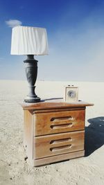 Close-up of electric lamp on table by sea against sky