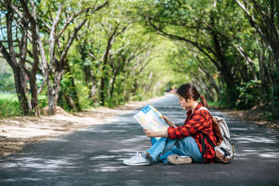 Man reading book while sitting on road