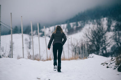 Rear view of woman on snow covered field