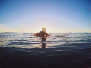 Man swimming in sea against sky