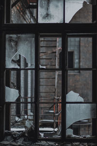 Close-up of broken glass window of abandoned building