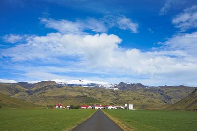 Road amidst field against sky