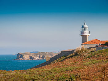 Lighthouse by sea against sky